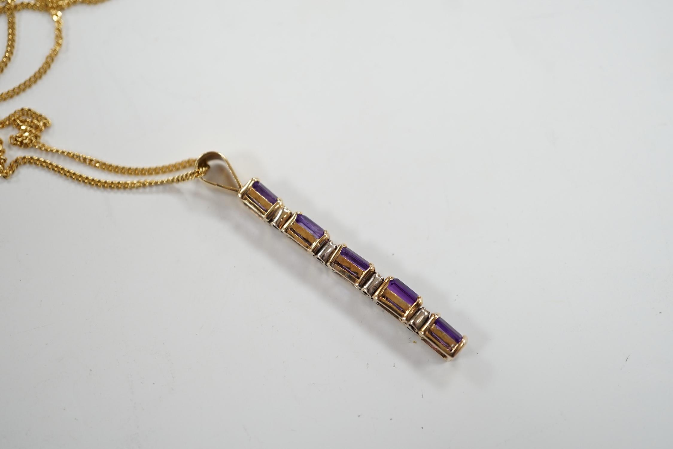 A modern yellow metal, amethyst and diamond chip set line pendant, 47mm, on an 18ct gold fine link chain, 38cm, gross weight 6.4 grams.